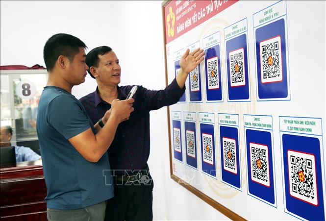 Cán bộ Trung tâm phục vụ hành chính công xã Ninh Cường, tỉnh Ninh Bình hướng dẫn người dân tra cứu thông tin thủ tục hành chính bằng mã QR code. (Ảnh: Nguyễn Lành/TTXVN)